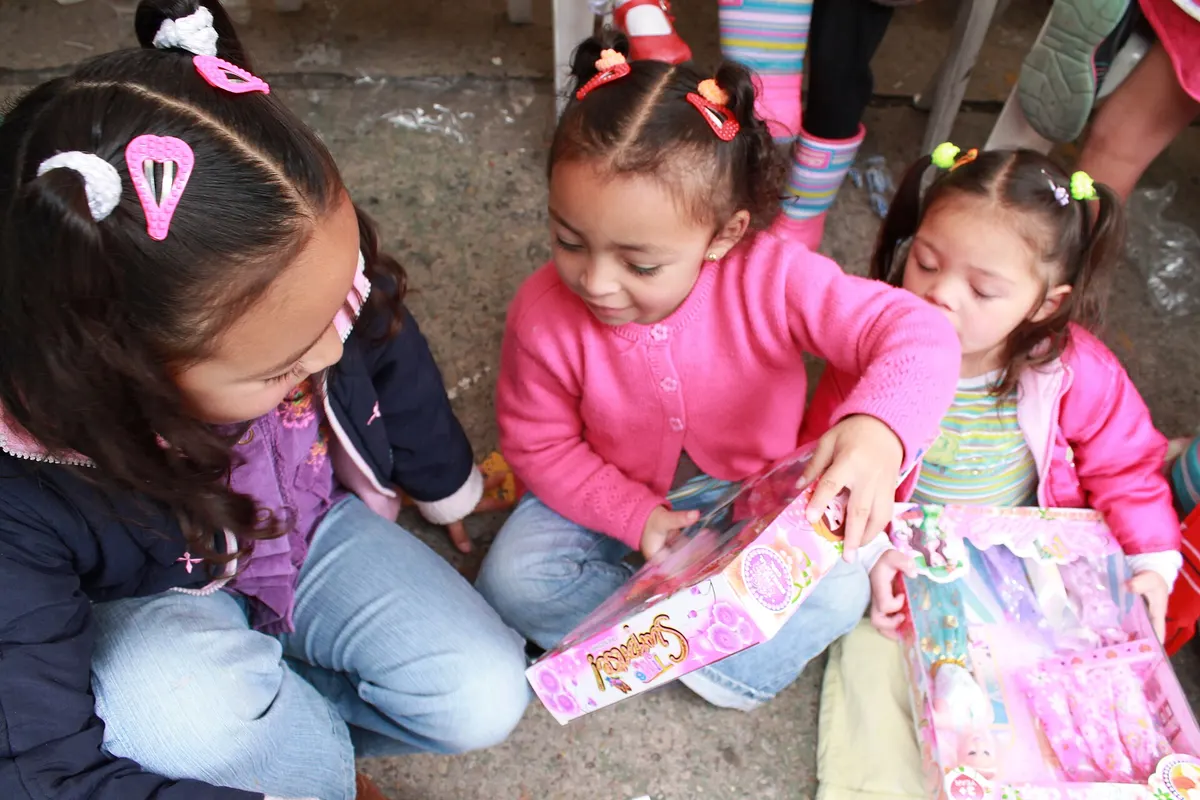 Niñas abriendo sus aguinaldos en una novena de navidad en Bogotá