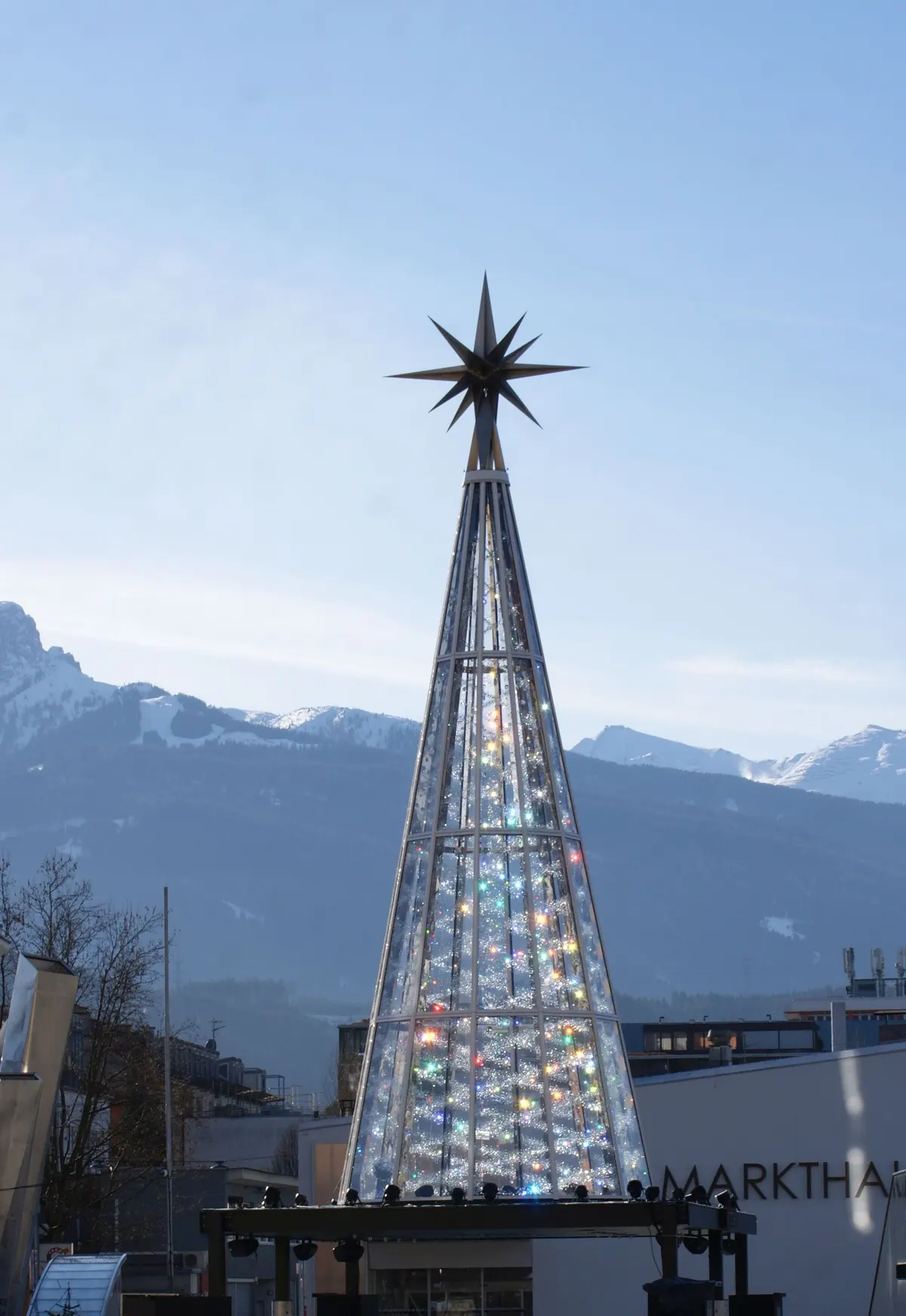 Swarovski-Kristallbaum mit Stern am Innsbrucker Marktplatz vor Bergkulisse