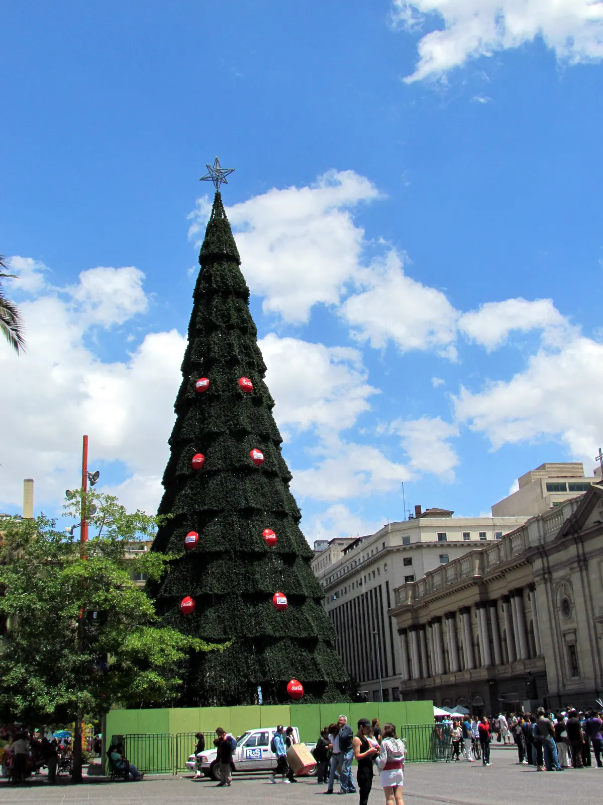 Árbol de Navidad gigante de la Plaza de Armas de Santiago con adornos rojos, bajo un cielo azul