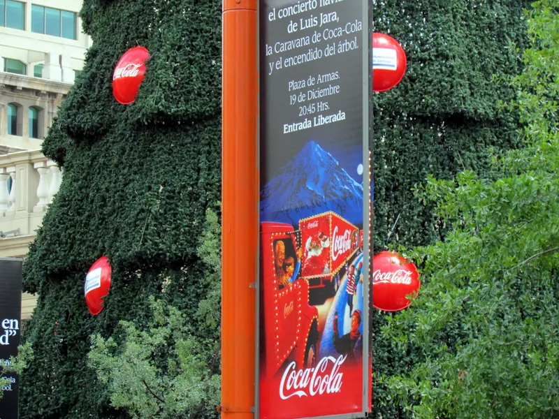 Detalle del árbol de Navidad de la Plaza de Armas de Santiago con adornos y publicidad de la caravana navideña