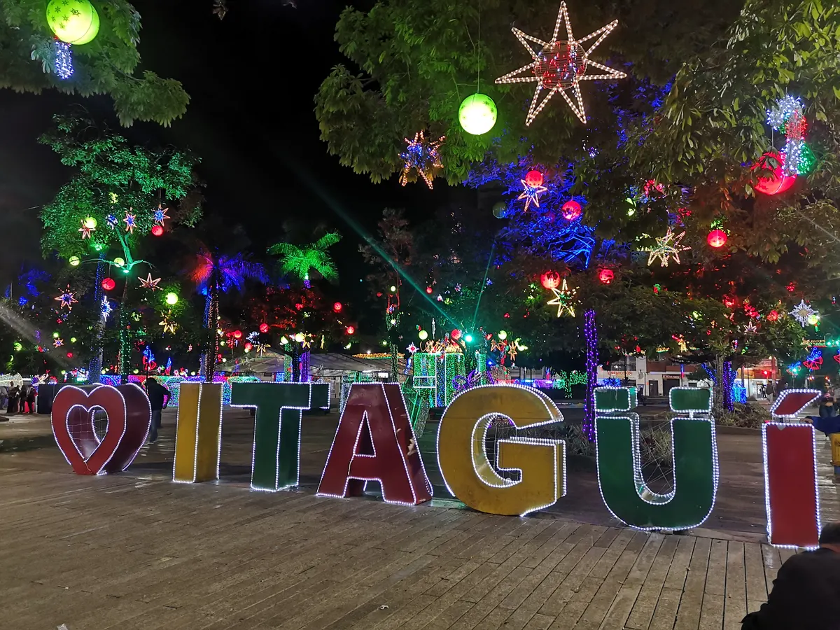 Letras del letrero de Itagüí bajo árboles con luces y estrellas en el alumbrado navideño