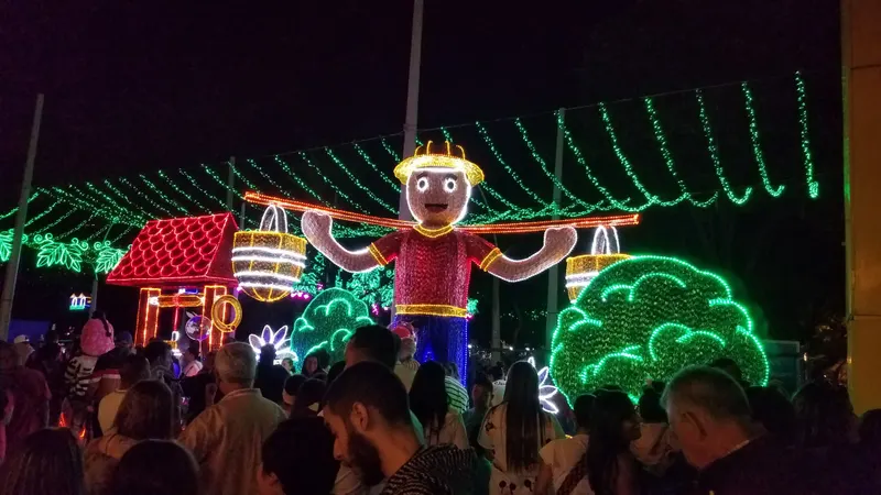 Figura luminosa de un campesino con canastas entre arcos de luces en el alumbrado de Medellín