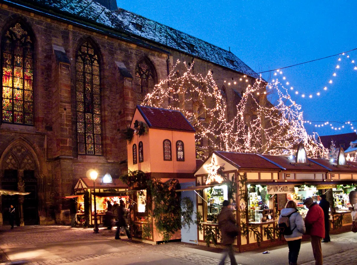 Chalets du marché de Noël devant l'église des Dominicains de Colmar, illuminés