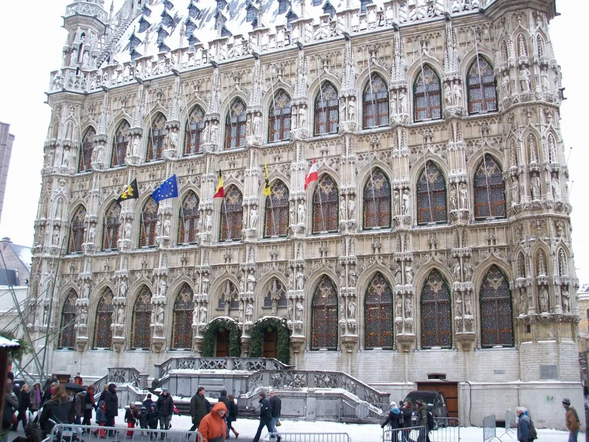 Het stadhuis van Leuven in kerstsfeer met groene kransen en sneeuw