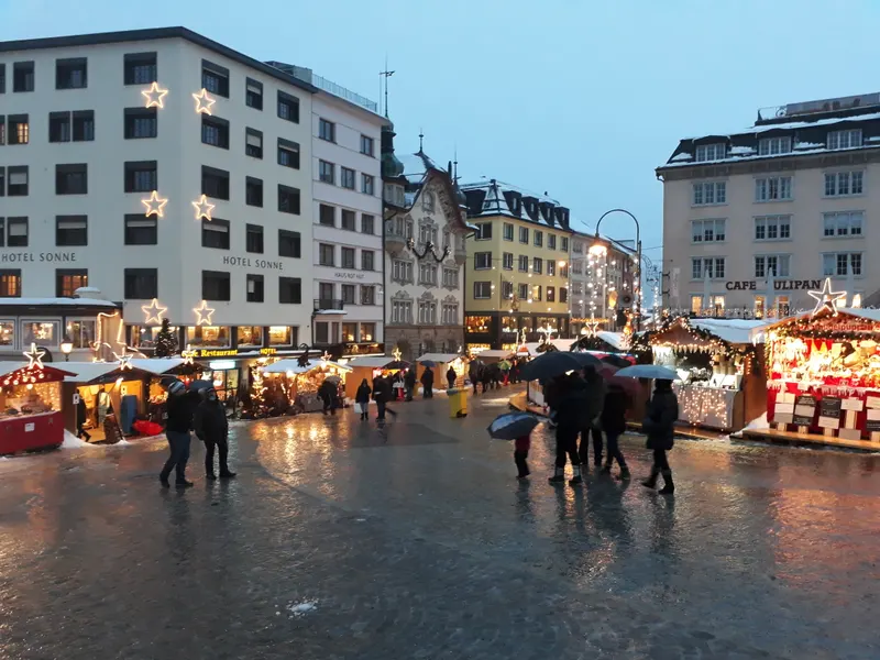 Beleuchtete Marktstände auf dem Hauptplatz von Einsiedeln im Regen