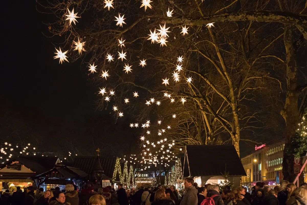 Markt der Engel am Kölner Neumarkt mit leuchtenden Sternen in den Bäumen