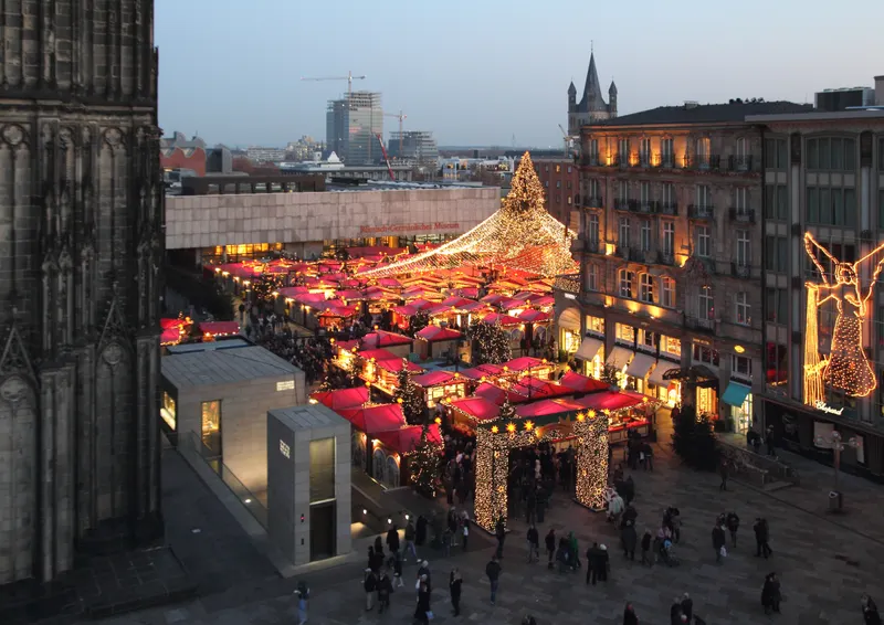 Rote Dächer und Lichterhimmel des Kölner Domweihnachtsmarkts in der Dämmerung