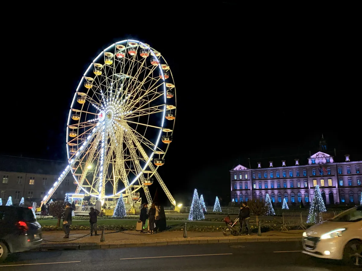 Grande roue illuminée et sapins devant l'hôtel de ville de Caen à Noël