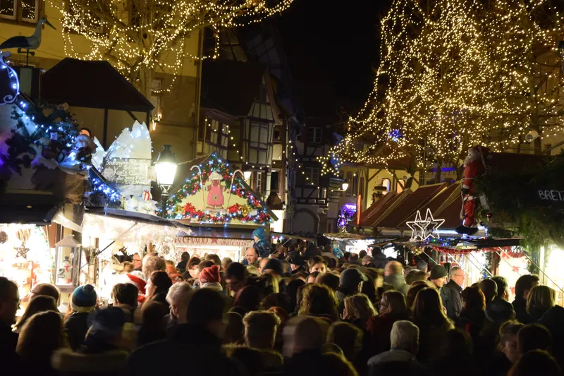 Foule dans une rue illuminée du marché de Noël de Colmar