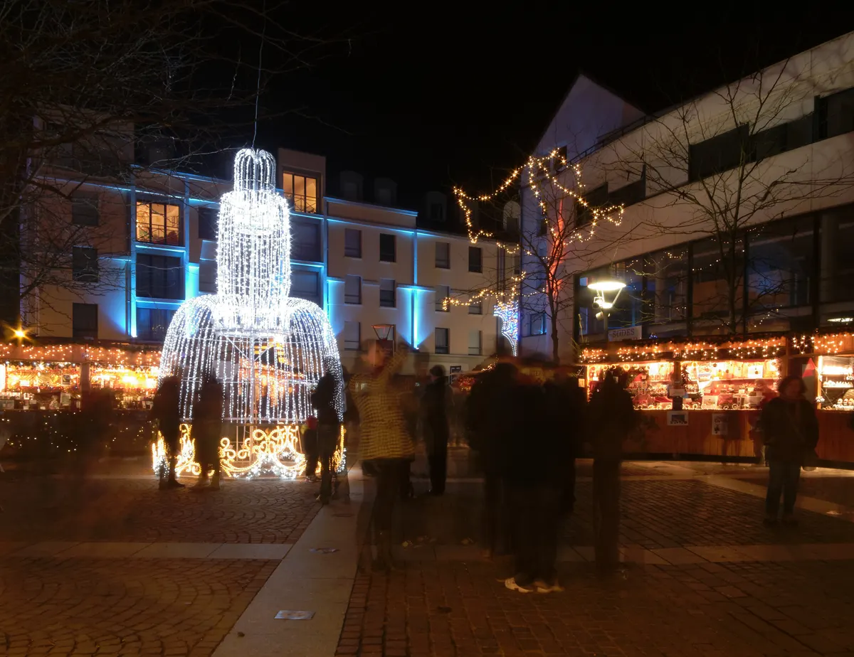 Temple Saint-Martin illuminé en bleu derrière les chalets du marché de Noël de Montbéliard