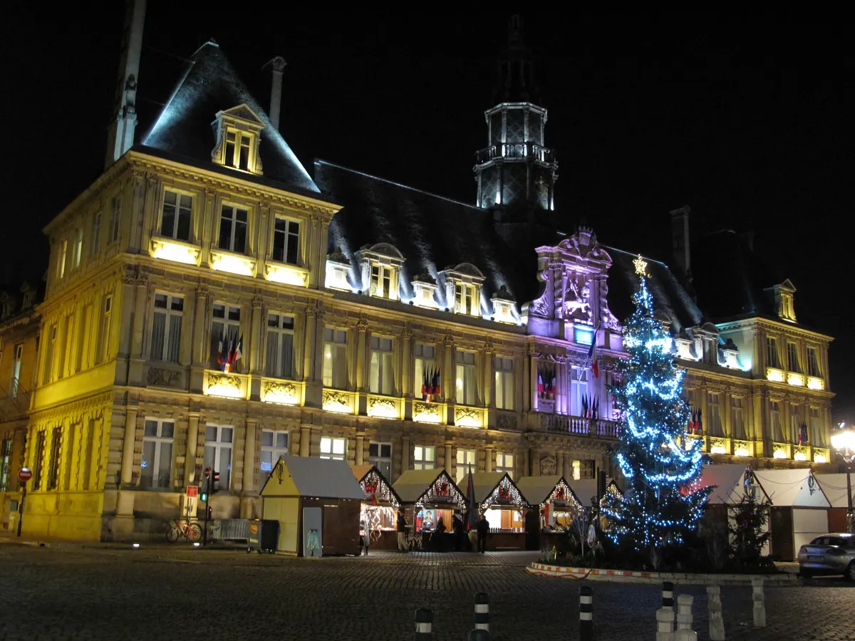 Hôtel de ville de Reims illuminé de nuit avec un sapin de Noël et des chalets