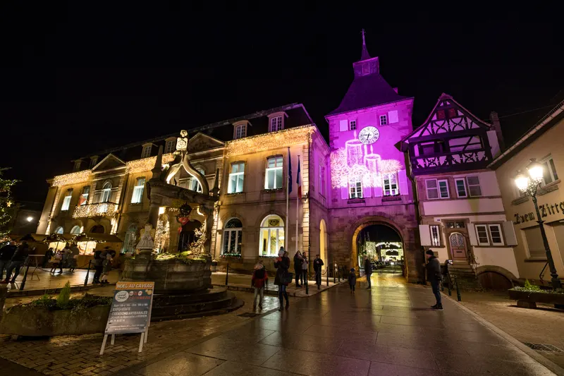 Porte de l'Horloge de Rosheim illuminée de nuit pendant le marché de Noël