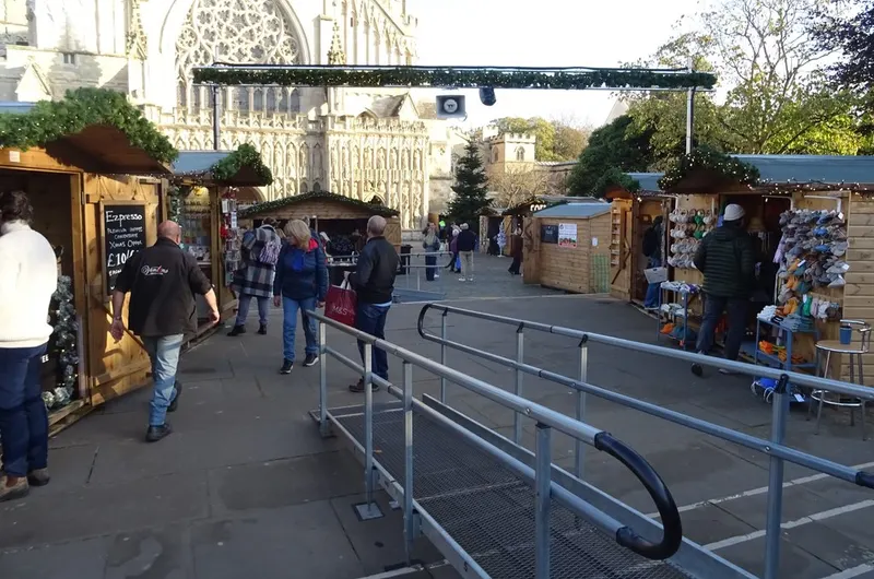 Wooden chalets and visitors at Exeter Cathedral Christmas Market