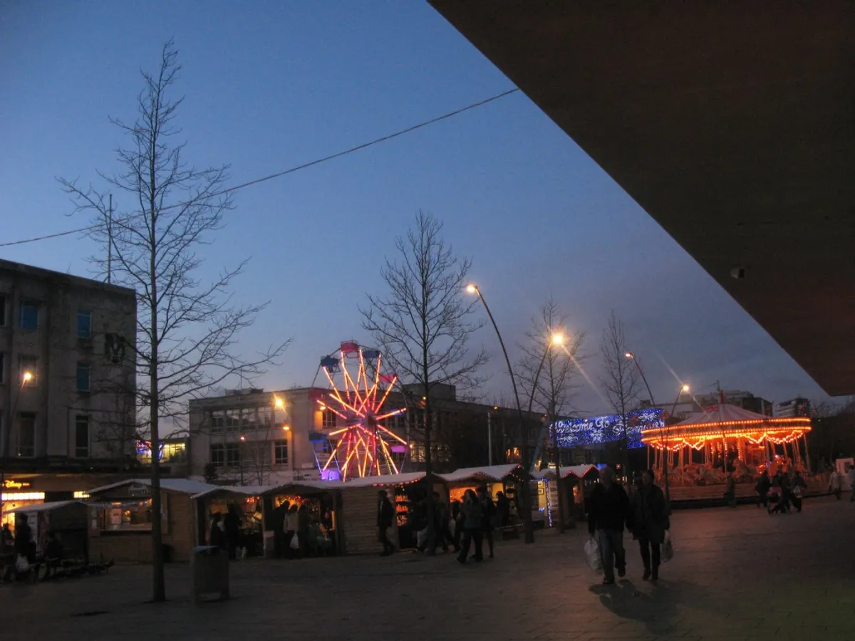 Plymouth Christmas market stalls with a carousel and big wheel at dusk