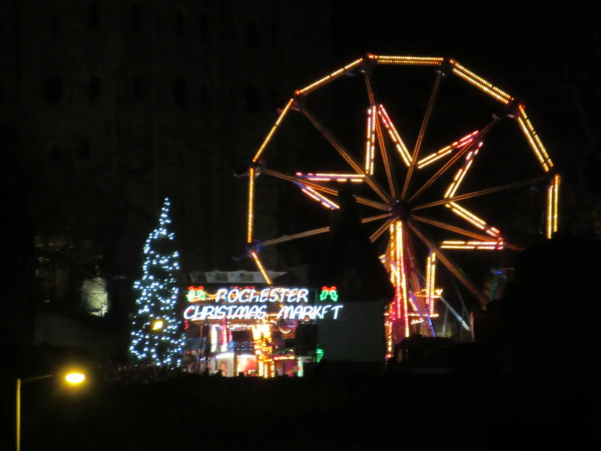Rochester Christmas Market funfair wheel lit up at night near Rochester Castle