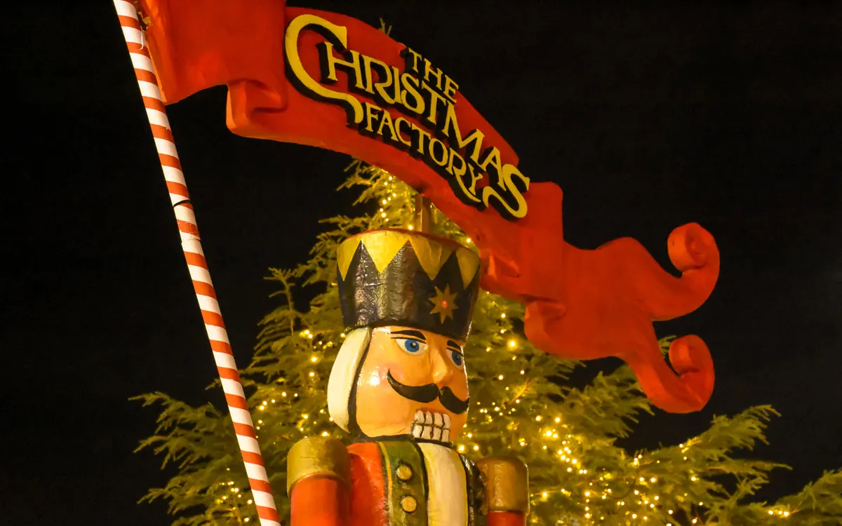 Ο γίγαντας καρυοθραύστης και η πινακίδα The Christmas Factory στην Αθήνα, με φωτισμένο έλατο