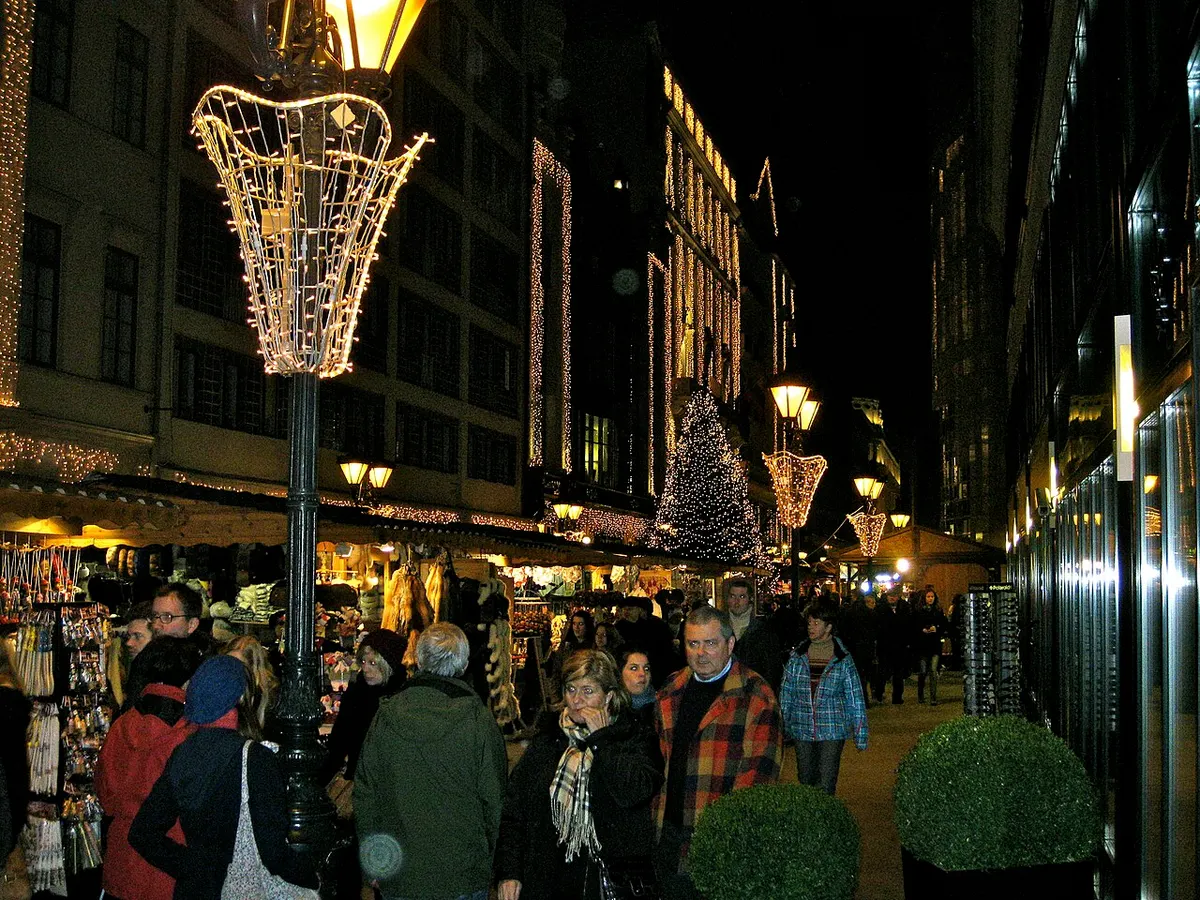 Tömeg a Vörösmarty téri karácsonyi vásárban Budapesten, díszkivilágított lámpákkal