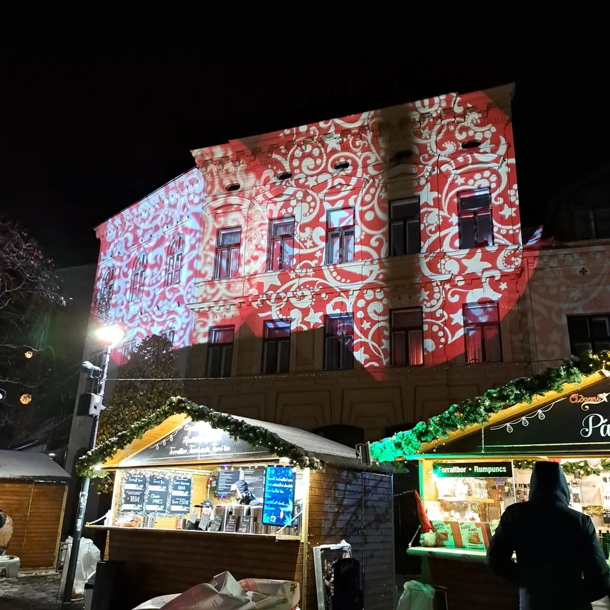 Díszkivilágítás-vetítés egy soproni házon az adventi vásár bódéi felett