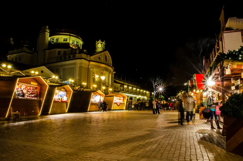Casette illuminate del Mercatino di Natale lungo la passeggiata di Merano