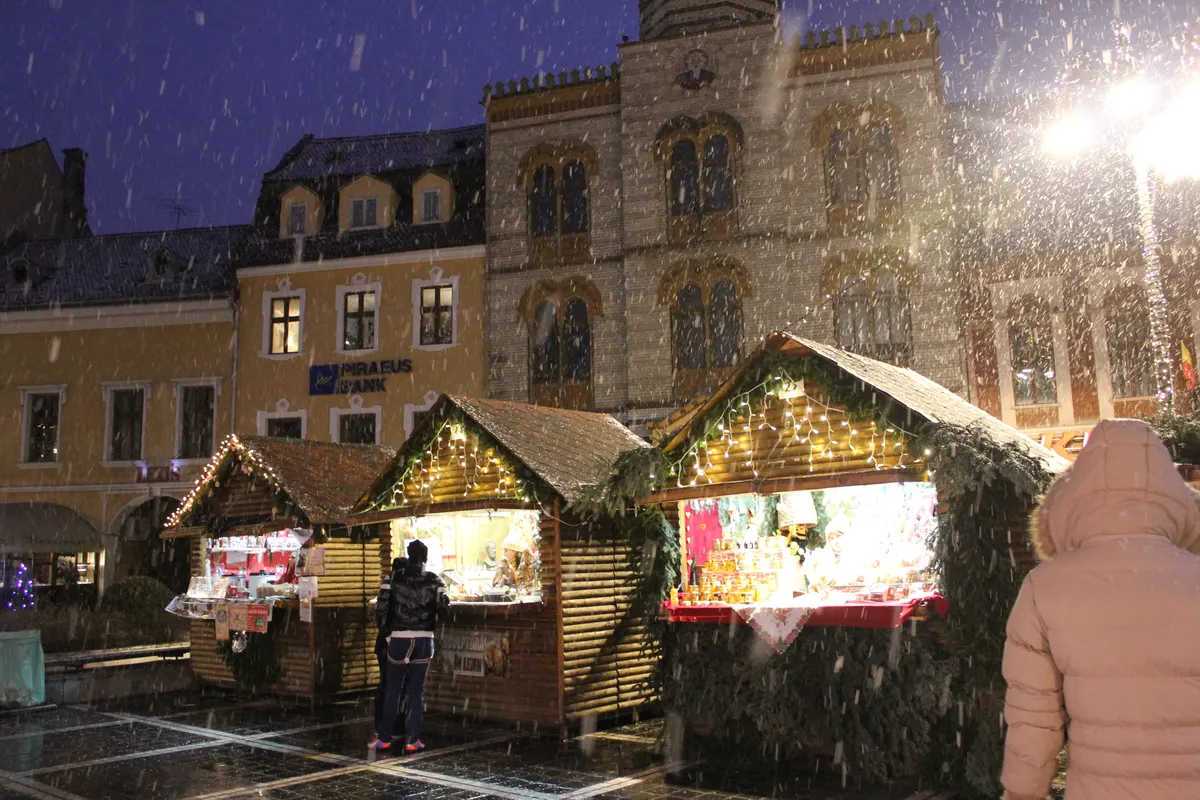 Căsuțe de lemn ale Târgului de Crăciun din Brașov, sub ninsoare, în Piața Sfatului
