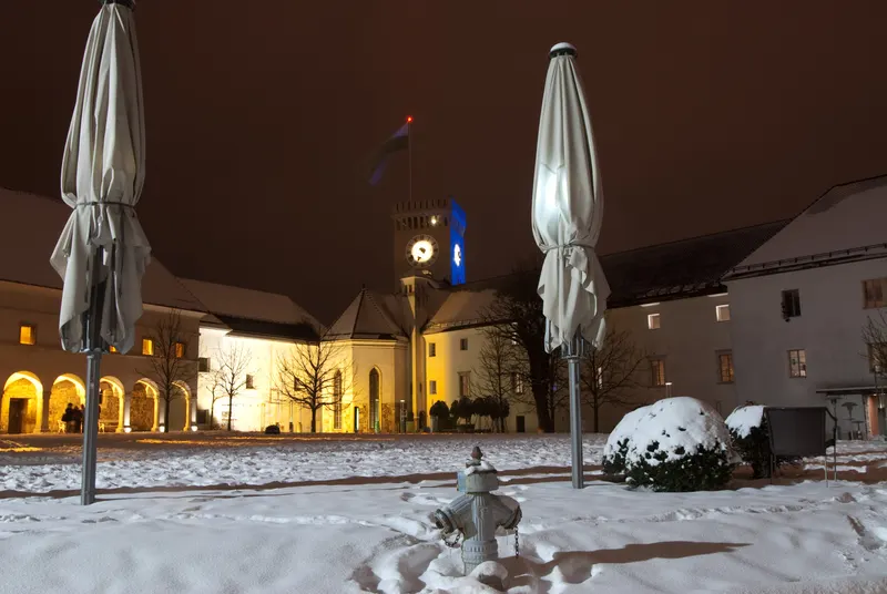Zasnežen grajski dvorec Ljubljanskega gradu v večernem mraku