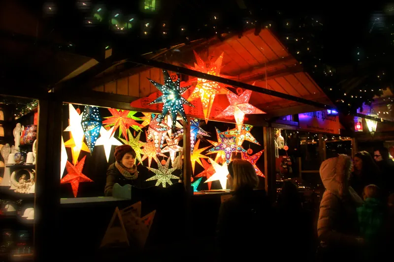 Glowing paper star lanterns at a stall at Christkindlmarket Chicago at night