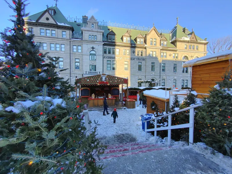 Chalets du marché de Noël et sapins enneigés devant l'Hôtel de Ville de Québec