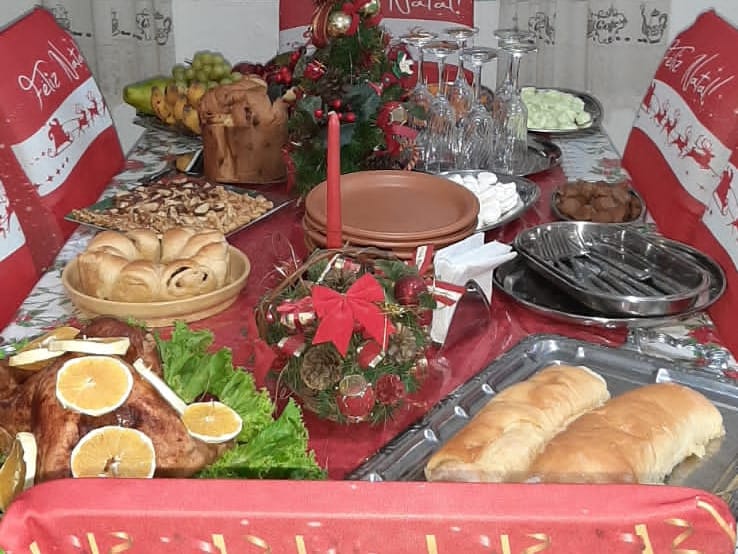 Mesa de ceia de Natal em casa, com ave assada, pães, panetone, frutas e castanhas