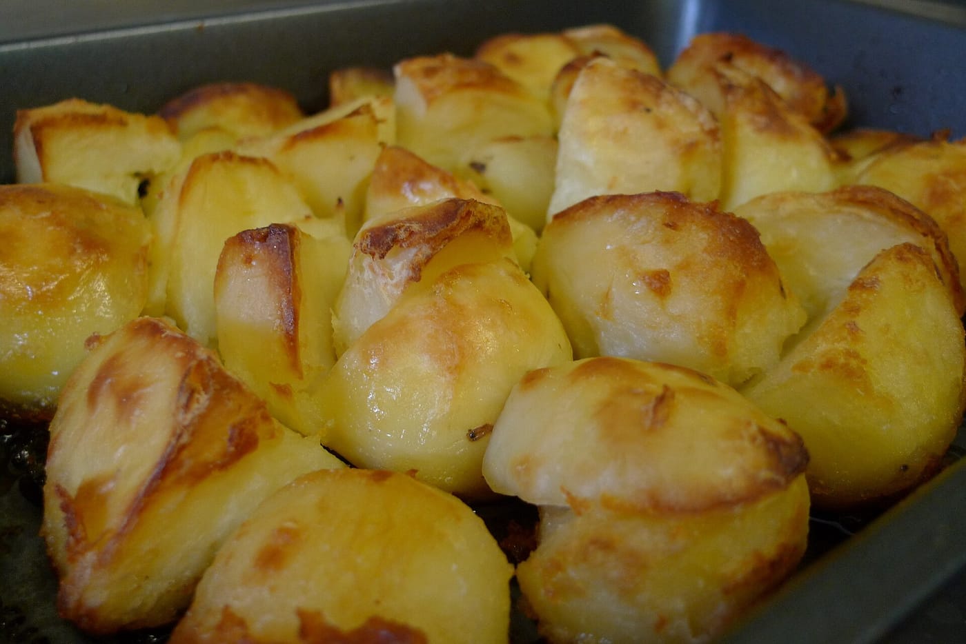 Golden, crispy roast potatoes in a roasting tin