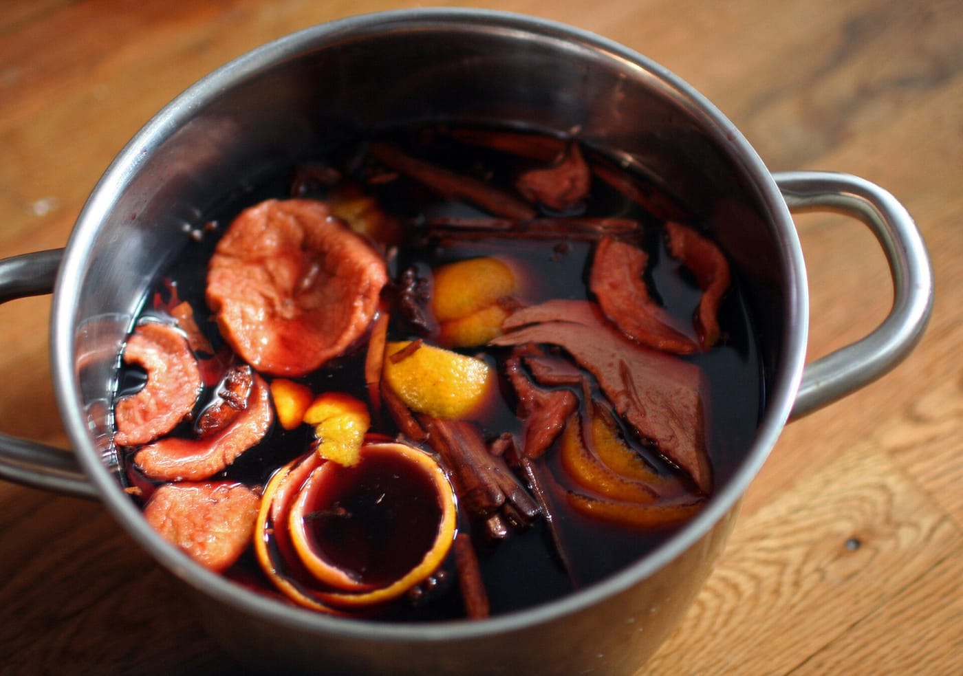 Glögg som drar i en kastrull med kanel, apelsinskal och kryddor