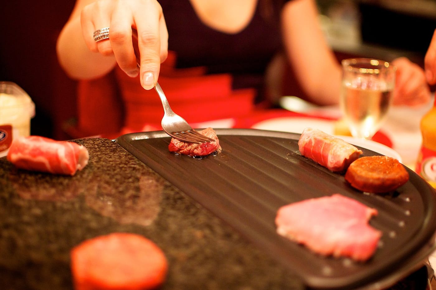 Vlees en hamburgertjes op een gourmetstel aan tafel