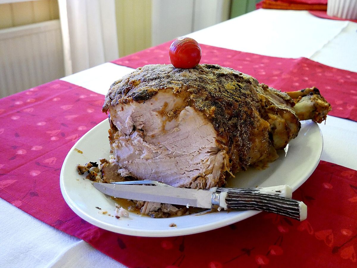 Gräddad julskinka med brynt skorpa, skuren på ett fat