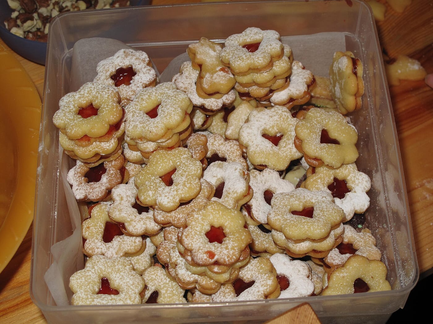 Linzer Kekse in Blumenform mit roter Marmelade und Staubzucker in einer Dose